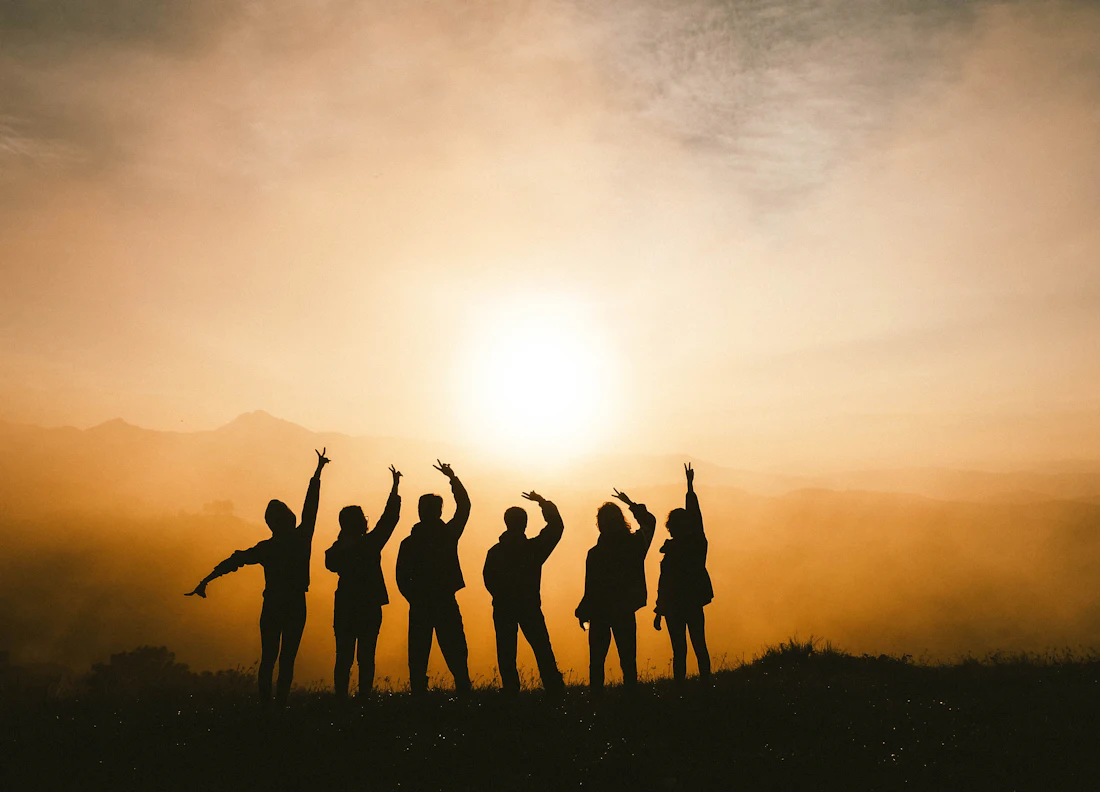Grupo de viajeros celebrando al atardecer